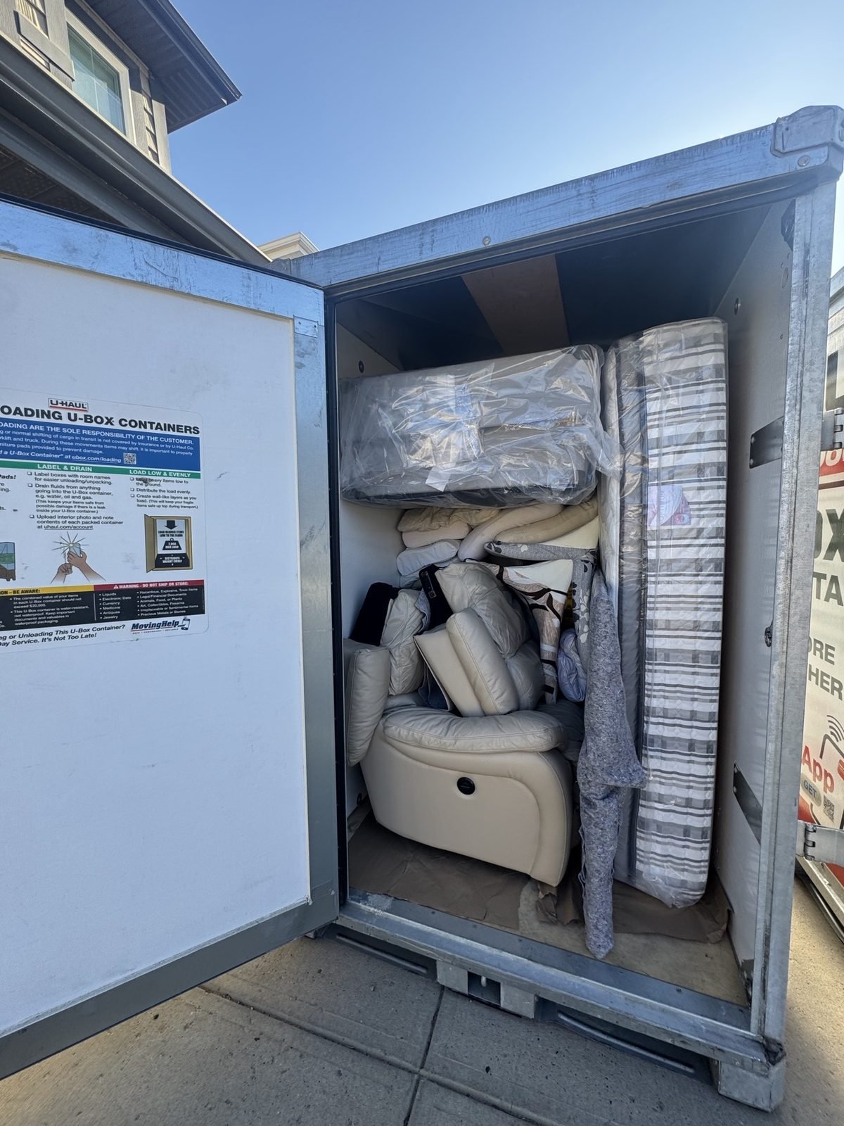 A U-Box container loaded with a mattress, leather recliner and cushions