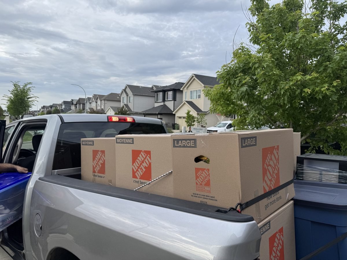 A pickup truck loaded with Home Depot moving boxes in a residential street
