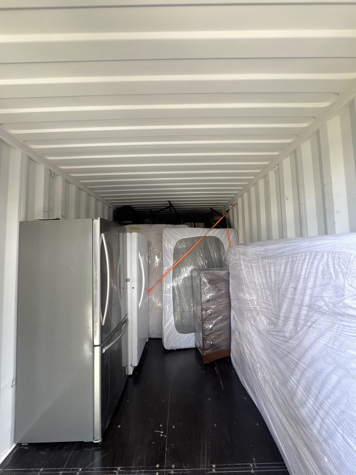Fridge and mattresses wrapped and strapped inside a moving container